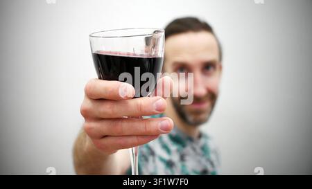 Nahaufnahme eines Weinglases in der Hand eines Mannes, der es zum Toast hebt Stockfoto