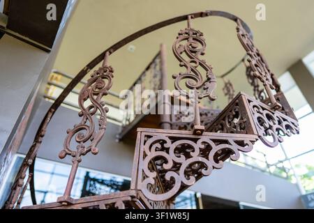 Metallene Eisenspiraltreppe im Innenraum nahe der Wand, Nahaufnahme. Runde Retro-Treppe als Dekoration im Interieur Stockfoto