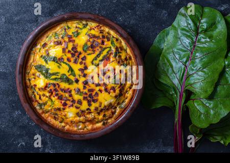 Keramikschüssel mit Gemüsefrittata, einfache vegetarische Speisen. Frittata mit Eiern, Blättern von grünen Rüben, Zwiebeln, Pfeffer, Gewürzen und Käse, Schließen. In Stockfoto