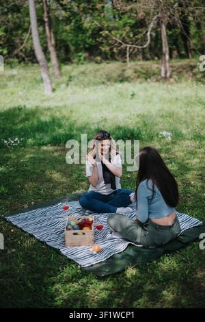 Zwei Freunde genießen ein entspanntes Picknick auf einer Decke in einem sonnigen grünen Park Stockfoto