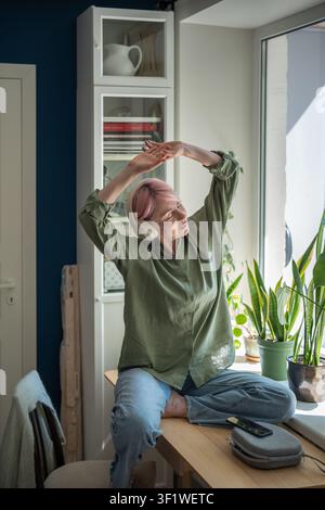 Sorglose positive reife Frau, die Musik-Playlist online auf dem Smartphone streamt und zu dem Song abtanzt. Stockfoto