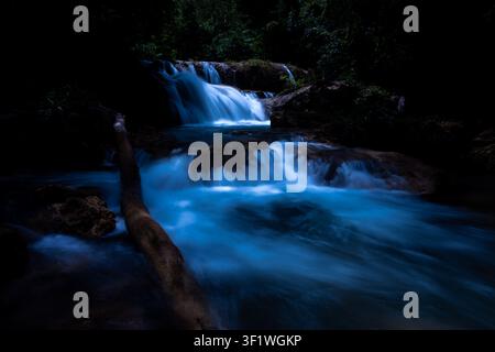 Eine Langzeitbelichtungs-Nachtaufnahme eines kaskadierenden Wasserfalls, der durch einen ruhigen Wald im Huai Mae Khamin-Wasserfall in Kanchanaburi, Thailand, fließt. Stockfoto