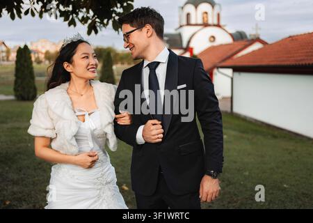 Glückliche Braut und Bräutigam lächelnd, Arm in Arm an ihrem besonderen Tag Stockfoto