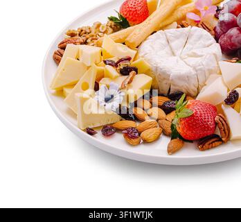 Ein Käsebrett ist auf einem weißen Teller angerichtet. Es zeigt verschiedene Käsesorten, Früchte wie Erdbeeren und Trauben, Nüsse und Blumen. Diese Szene ist ideal für ein gesellschaftliches Treffen oder einen Snack. Stockfoto