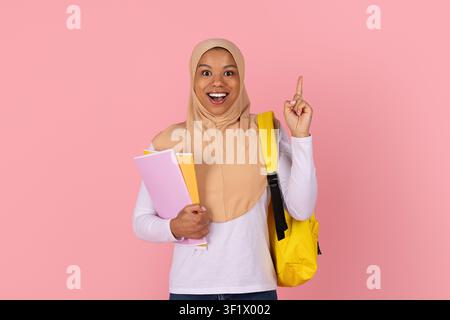Schwarze Studentin mit Hijab, die Notizbücher hält und einen Finger hebt, eine Idee hat Stockfoto