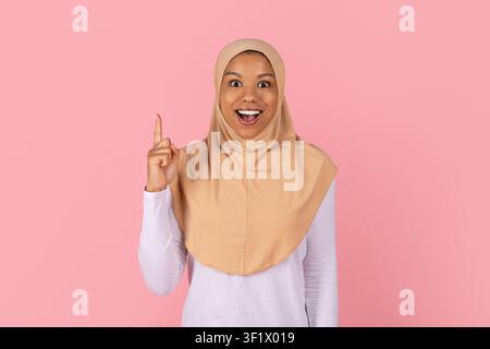 Glückliche schwarze muslimische Frau in beigem Hijab, die einen Finger hebt und eine Idee teilt Stockfoto