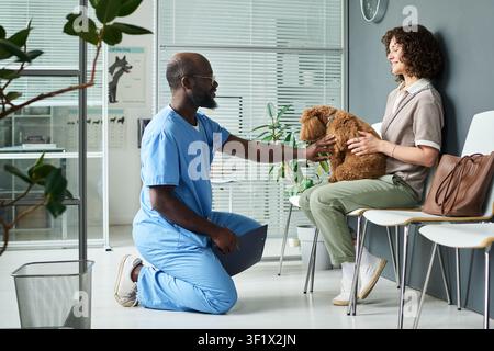 Schwarzer Tierarzt untersucht Hund mit Frau in der Klinik Stockfoto