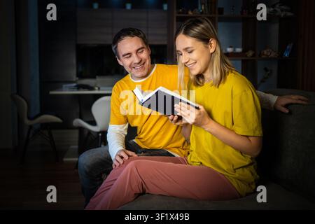 Zuhause, Entspannung und Paar auf einer Couch, Bibel und Lesen mit Religion, Liebe und Bindung zusammen. Romantik, Wohnung oder Mann mit Frau Stockfoto