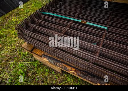 Gestapelte geschweißte Bewehrungsnetze auf Holzpalette im Freien. Konzept: Betonbewehrung Stockfoto