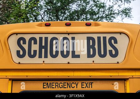 Die Rückseite eines klassischen gelben amerikanischen Schulbusses mit Schulbus-Schriftzug und Notausgangsschild. Stockfoto