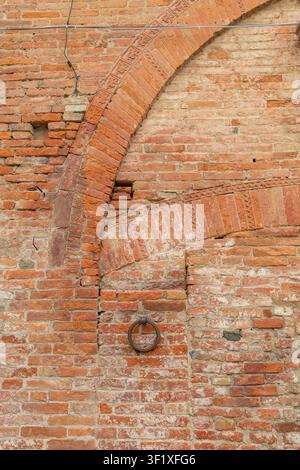 Alte Backsteinarchitekturdetails mit dekorativen Bögen und einem Metallring in einer alten Stadt Stockfoto