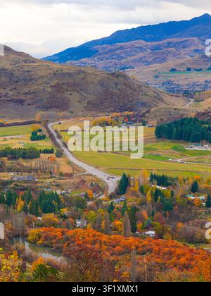 Hochwinkelansicht einer kurvenreichen Straße, die durch ein farbenfrohes Herbsttal in der Nähe von Arrowtown und Crown Range auf der Südinsel Neuseelands führt Stockfoto