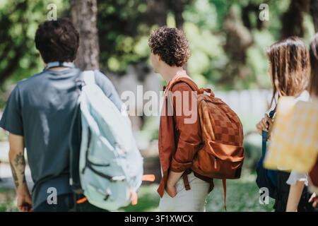 College-Studenten mit Rucksäcken, die an einem sonnigen Tag auf einem Campusweg im Freien plaudern Stockfoto