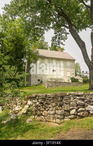 Historisches General-Adam-Stephen-Haus in Martinsburg, WV, USA auf einem grasbewachsenen Hügel mit einer Steinmauer umgeben von üppigem Sommerlaub. Stockfoto