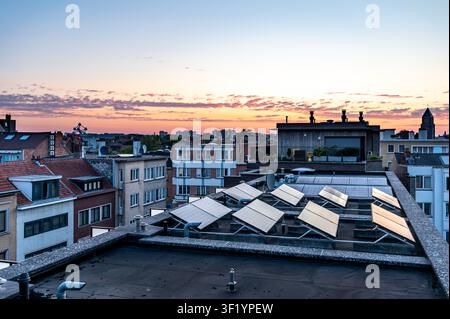 Farbenfroher Sonnenaufgang über Wohnhäusern in Brüssel mit Photovoltaik-Solarpanelen, die auf Flachdächern moderner Häuser installiert sind. Brüssel, Belgien 15 Stockfoto