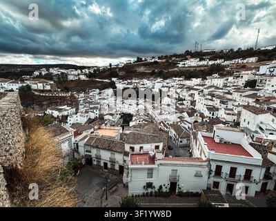 Setenil de las Bodegas, Spanien - 27. Oktober 2025: Blick auf die weißen Häuser von Setenil de las Bodegas, die in die Felskliffs eingebaut sind, unter einer dramatischen Wolkendecke Stockfoto