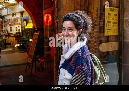 Lächelnde Frau steht am Eingang des Cafés und schaut in die Kamera Stockfoto