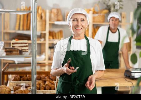Ältere Verkäuferin posiert mit einer Zange Stockfoto