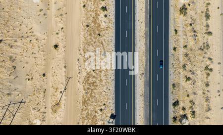 Luftbild einer geteilten Autobahn, die vertikal durch eine trockene Wüstenlandschaft verläuft Stockfoto