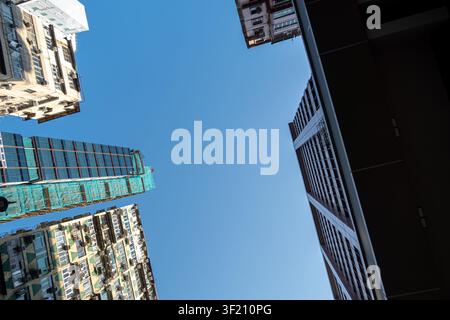 Niedrigwinklige Ansicht eines dichten Hochhauses in Kowloon, Hongkong, das unter Bau befindet sich und in grünes Gerüst eingehüllt ist Stockfoto