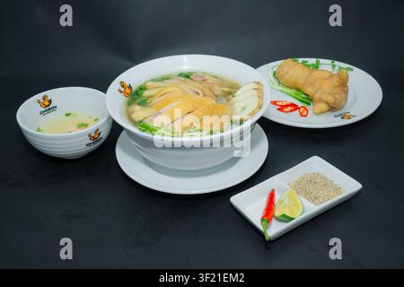 Eine authentische vietnamesische Pho-Nudelsuppe mit hochwertigem Dong Tao-Huhn, berühmten Drachenhühnerfüßen und goldener Brühe, serviert in einer Schüssel auf einem Holztisch Stockfoto