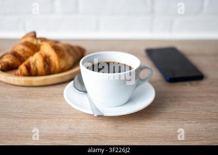 Buttriger Vollbuttertoast mit schwarzem Kaffee und Smartphone zum Frühstück Stockfoto