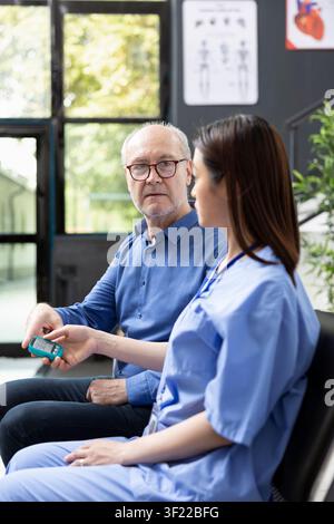 Medizinische Assistentin überprüft den Blutzuckerspiegel eines männlichen Klinikbesuchers mit einem digitalen Glukometer. Die Krankenhausumgebung spiegelt moderne Gesundheitsdienste, Diabetesmanagement und Patientensicherheit wider. Stockfoto
