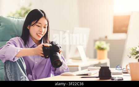 Lächelnde asiatische Frau mit Kamera im Homeoffice, Geschäftskonzept Stockfoto