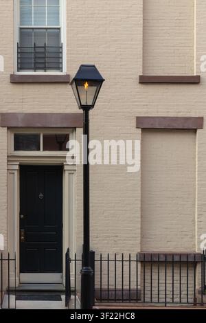 BROOKLYN, NEW YORK - 1. JUNI 2026: Gaslaterne im Vintage-Stil mit aktiver Flamme auf dem Gehweg vor einem historischen beigen Backsteinhaus Stockfoto