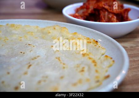 Goldbraune und knusprige koreanische Kartoffelpfannkuchen auf einem Teller, der auf einem Holztisch platziert ist. Stockfoto
