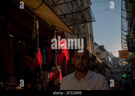 Fußgänger gehen durch eine enge Einkaufsstraße, die mit türkischen Nationalflaggen geschmückt ist, im historischen Bezirk Eminönü von Istanbul Stockfoto