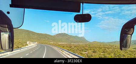 Innenansicht vom Vorderfenster des Busses, der auf der Autobahn in den kroatischen Bergen unterwegs ist. Stockfoto