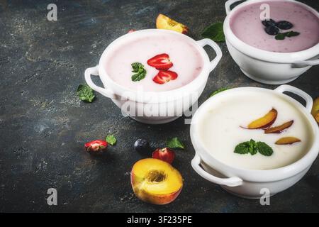 Verschiedene süße cremige Frucht & Berry Suppen, Erdbeere, Pfirsich, Blaubeere, Dunkelblau konkreten Hintergrund der Ansicht von oben kopieren Raum Stockfoto