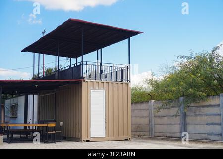 Ein stilvolles zweistöckiges Café und Büro, das aus einem recycelten Schiffscontainer gebaut wurde und eine offene Dachterrasse bietet. Stockfoto