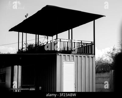 Dramatischer Schwarz-Weiß-Aufnahme eines zweistöckigen Schiffscontainergebäudes mit einer offenen Terrasse im Obergeschoss Stockfoto
