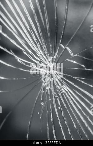 Abstrakte gesprungene Glastextur mit zersplittertem Schlagmuster im monochromen Nahaufnahme-Hintergrund Stockfoto