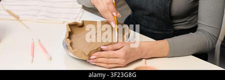 Handwerkerin, Töpferin formt Ton mit Präzision in einem warmen Atelier, Banner Stockfoto