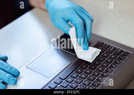 Männliche Hände In Handschuhen Desinfizieren Laptop Vor Der Arbeit Zu Hause Stockfoto