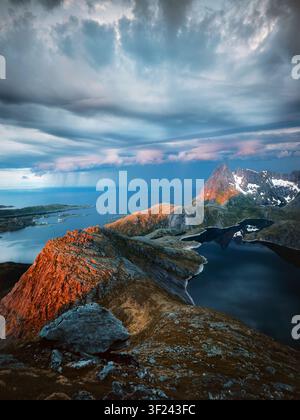 Stürmisches Wetter auf den Lofoten-Inseln in den Bergen, Luftaufnahme von See und Felsen, Sonnenuntergang, dramatischer Himmel, Landschaft, Reisen in Nordnorwegen, schöne, stimmungsvolle Natur Stockfoto