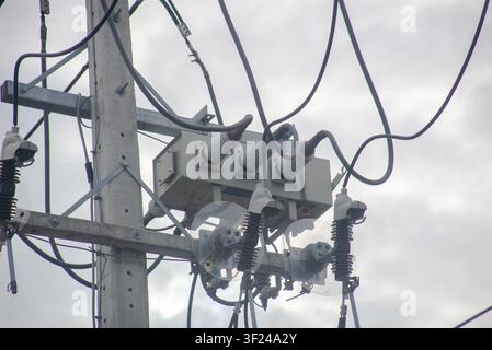 Nahaufnahme einer auf einem Strommast montierten Stromübertragungsausrüstung, die Isolatoren, Kabel und Hardware zeigt, die bei der Stromverteilung verwendet werden Stockfoto