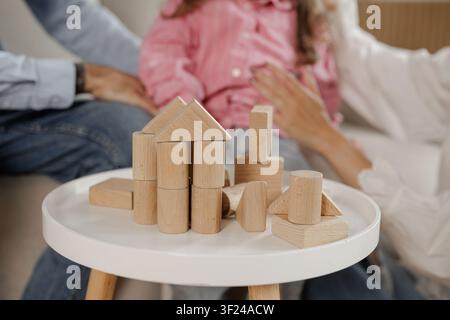 Eine Familie genießt Qualitätszeit zusammen, während sie ein Haus mit einem hölzernen Bausatz baut, was Kreativität und Verbundenheit in einem gemütlichen Wohnzimmer fördert. Stockfoto