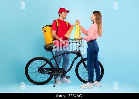 Junger Mann und Frau tauschen Einkaufstüten mit Fahrrad aus, fröhliche Stimmung, Gewichtsabnahme-Konzept Stockfoto