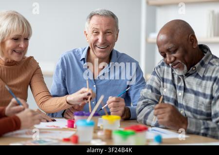 Zufriedener älterer kaukasischer Mann und Frau, die sich mit einer Kunstaktivität beschäftigen, Senior-Kreativwerkstatt Stockfoto