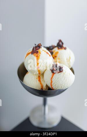 Genießen Sie eine visuell ansprechende Präsentation von cremigen Eisbechern, die mit einem Tropfen und knusprigen Stückchen gekrönt sind, perfekt für Dessertkarten oder Food-Blogs Stockfoto