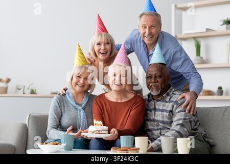Glückliche ältere kaukasische Paare feiern Geburtstag mit Kuchen und Kerzen zu Hause, Familienkonzept Stockfoto