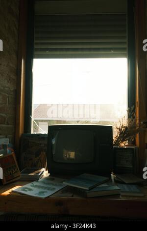 Altes CRT-Fernsehgerät steht vor einem Fenster in einem ästhetischen Vintage-Raum und fängt eine nostalgische Retro-Innenraumstimmung ein. Stockfoto