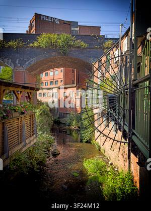 Das viktorianische Pub „Lass O'Gowrie“ neben dem freiliegenden Fluss Medlock und der Eisenbahn-Viadukt in der Innenstadt von Manchester. Stockfoto