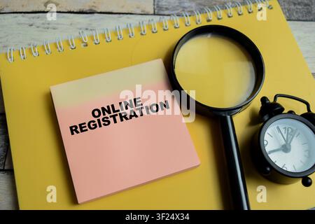 Konzept der Online-Registrierung, geschrieben auf Haftnotizen, isoliert auf Holztablett. Stockfoto