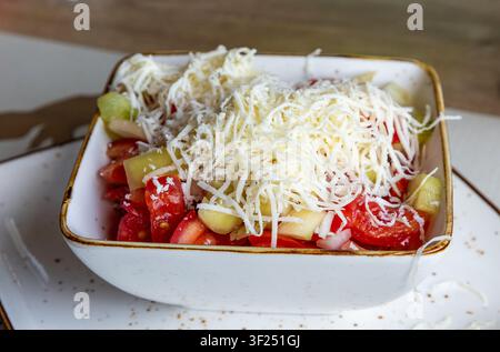 Frisch zubereiteter Shopska-Salat mit gewürfelten Tomaten, Gurken und Zwiebeln, großzügig mit geriebenem Weißkäse überzogen Stockfoto