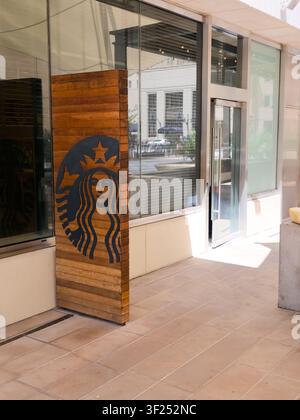 DALLAS, TX, USA - 11. JULI 2026: Ein hölzernes Schild mit dem Starbucks-Logo ist prominent vor einem modernen Glasgebäude angebracht. Die Mar Stockfoto